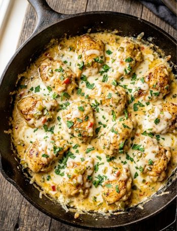 Golden seared chicken pieces smothered in a rich creamy queso sauce with green chiles and melted Monterey Jack cheese in a dark skillet