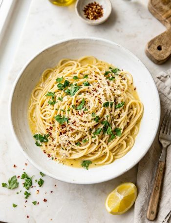 Creamy cowboy butter pasta in a white bowl topped with fresh parsley, parmesan, and red chili flakes