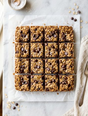 Healthy chocolate chip oatmeal bars cut into squares on parchment paper with melted chocolate chips on top