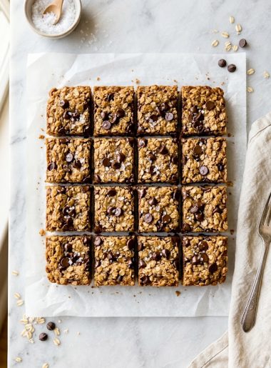 Healthy chocolate chip oatmeal bars cut into squares on parchment paper with melted chocolate chips on top