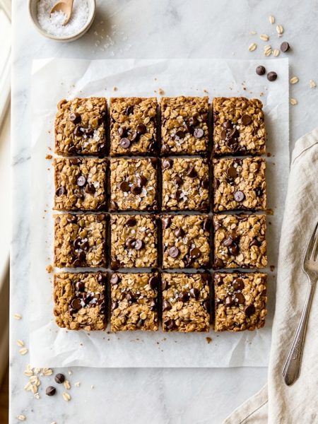 Healthy chocolate chip oatmeal bars cut into squares on parchment paper with melted chocolate chips on top