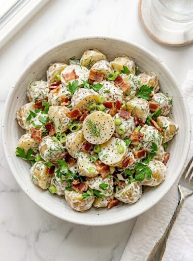 A creamy Jamie Oliver potato salad with baby potatoes, crispy bacon, fresh dill, and green onions in a large serving bowl