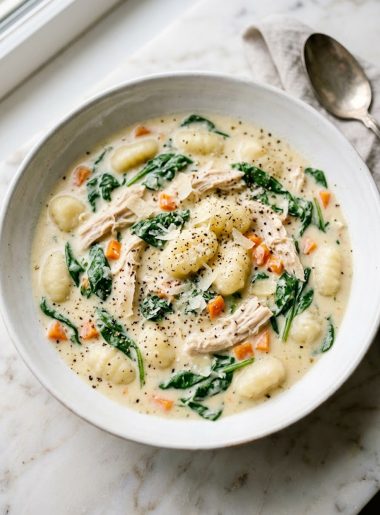 Creamy Olive Garden style chicken gnocchi soup with shredded chicken, pillowy gnocchi, fresh spinach and diced carrots in a white bowl on a marble surface