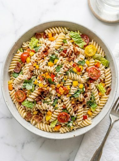 A large serving bowl of simple ranch BLT pasta salad filled with rotini pasta, crispy bacon, halved cherry tomatoes, chopped romaine lettuce, and colorful bell peppers coated in creamy ranch dressing