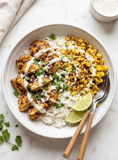 Protein packed street corn chicken bowl with smoky spiced chicken charred corn fluffy rice and creamy cilantro lime drizzle in a white ceramic bowl on a marble surface